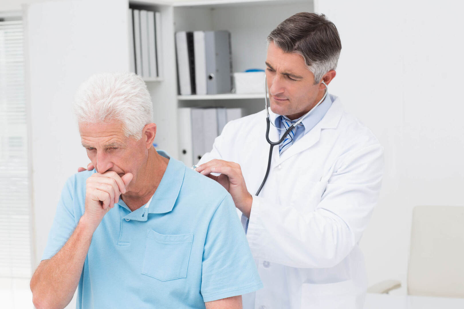 Older coughing patient checking in with doctor